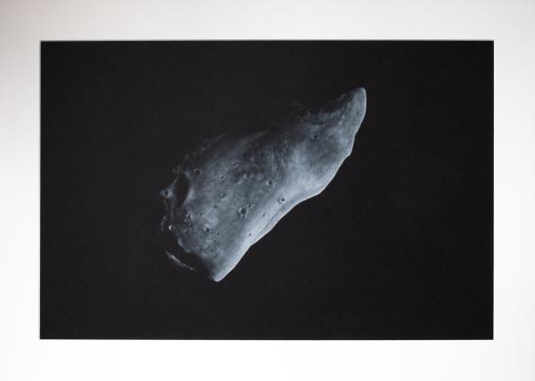 black and white asteroid named Gaspra, with little light from above on black background